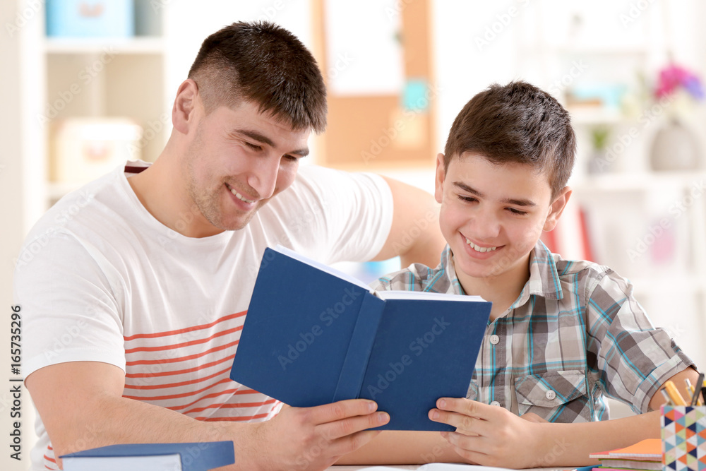Father and son doing homework together indoors Father and son doing homework together indoors