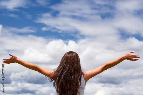 Freedom feel good and travel adventure, religion concept. Woman rising hands on blue sky and white cloud.