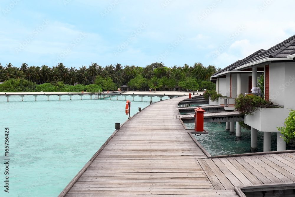 Naklejka premium View of wooden pontoon and modern beach houses on piles at tropical resort