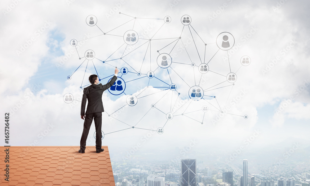 Businessman on house roof presenting networking and connection concept. Mixed media Businessman on house roof presenting networking and connection concept. Mixed media