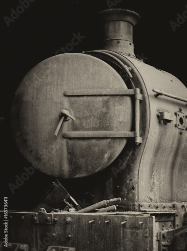 old rusty steam locomotive with door and chimney front view on black background photo