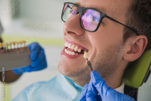 man smile with healthy teeth whitening. Dental care concept. Set of implants with various shades of tone