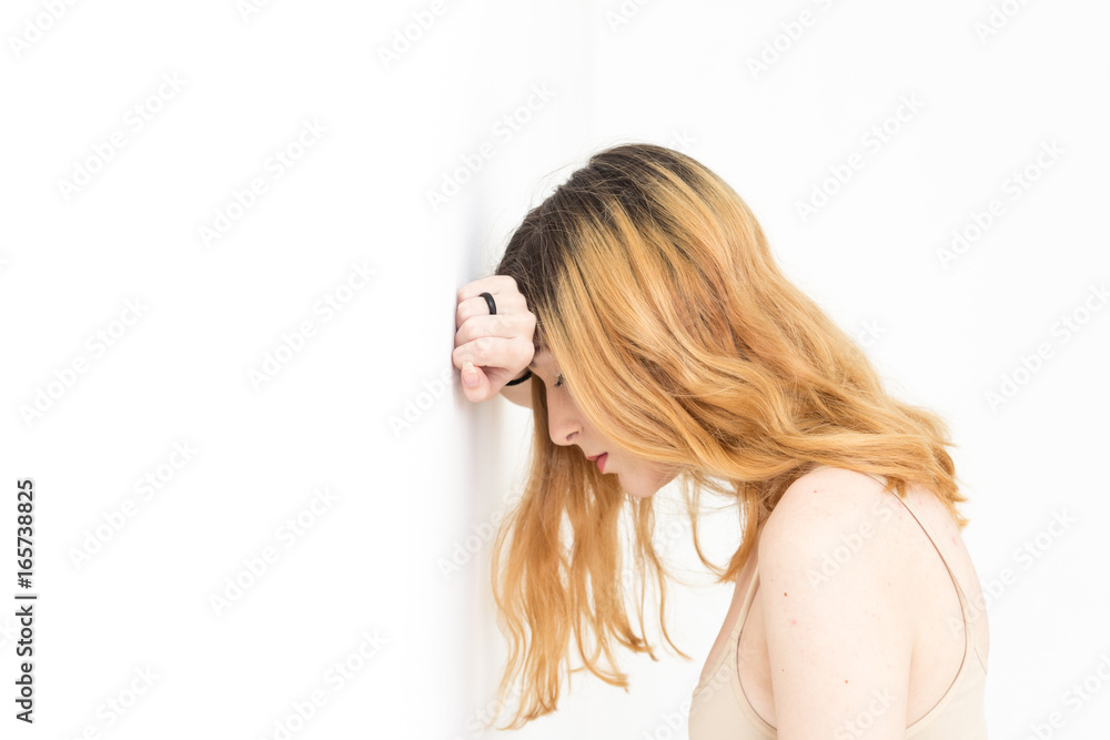 Young pretty blond looking down with her arm on the wall and head propped up. Young pretty blond looking down with her arm on the wall and head propped up.