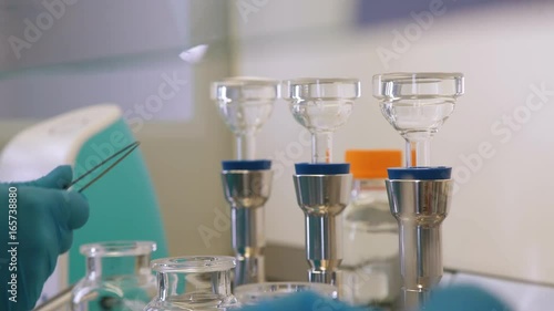 Chemical laboratory: test tubes, flasks, dishes for experiments. Scientists in blue sterile gloves work with chemical utensils and reagents. Laboratory tests in sterile conditions: chemical experiment photo