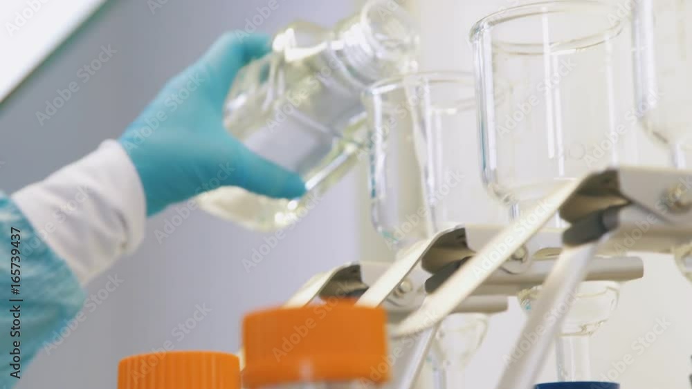 Chemical laboratory: test tubes, flasks, dishes for experiments. Scientists in blue sterile gloves work with chemical utensils and reagents. Laboratory tests in sterile conditions: chemical experiment Chemical laboratory: test tubes, flasks, dishes for experiments. Scientists in blue sterile gloves work with chemical utensils and reagents. Laboratory tests in sterile conditions: chemical experiment