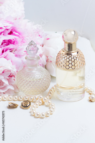 Wedding lifestyle with pink peony flowers, glamour bottles and jewellery close up