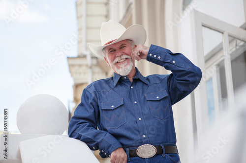 Wallpaper Mural A mature cowboy in a hat, jeans and a denim shirt looks at the camera. On open air. Torontodigital.ca