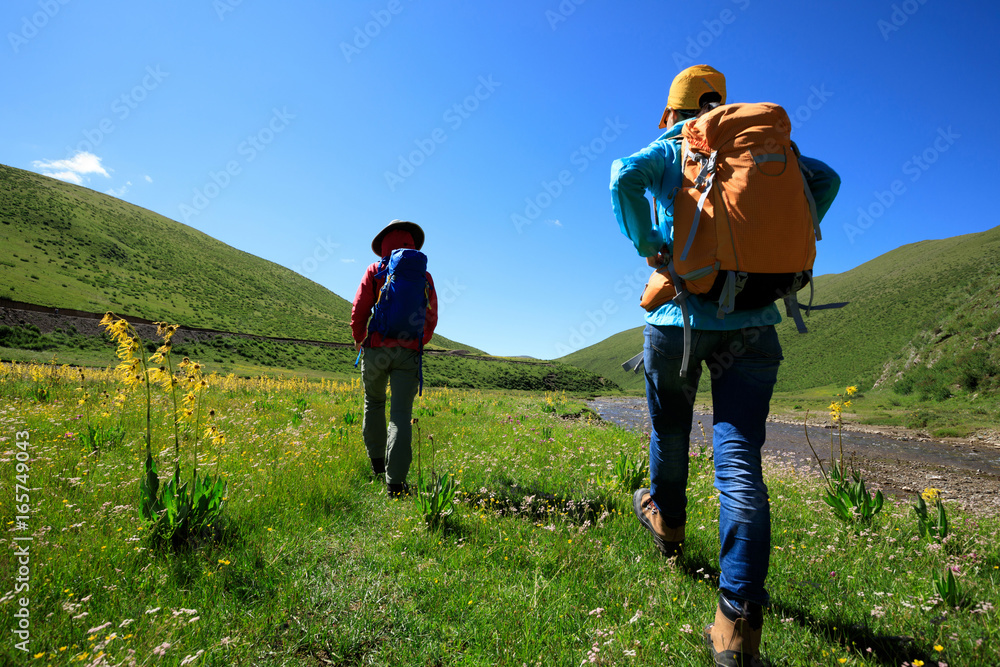 two backpacking women hiking in riverside mountains