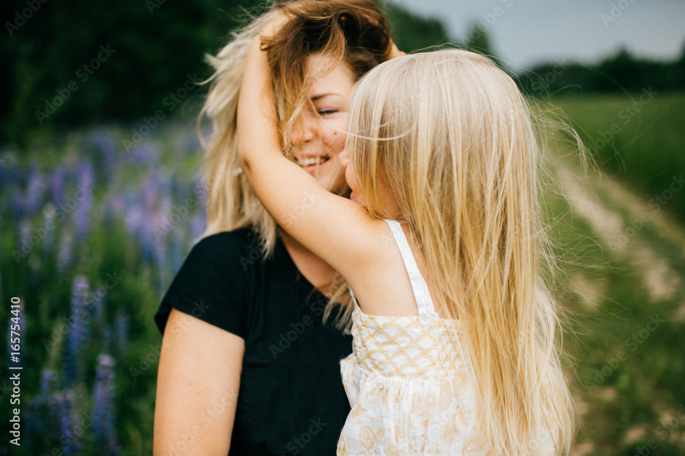 Young mother with long hair holding little daughter princess at hands. Playing with child. Pure, happy, kind, expressive emotional faces. Family at nature. Artistic kid. Laughing, smiling, embracing.