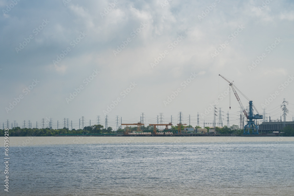Power plant crane situated near the river with cloudy sky background Power plant crane situated near the river with cloudy sky background