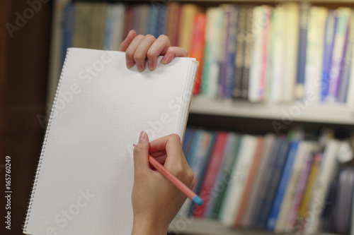 blank paper of notebook held by hands withpencil