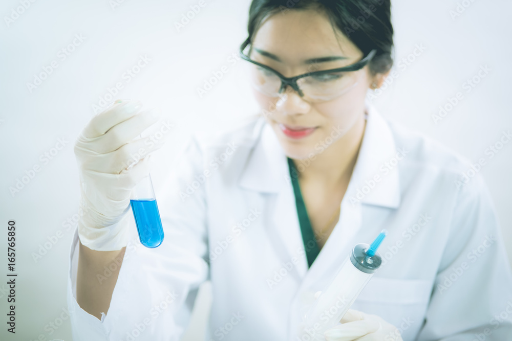Young Asian scientist working in the lavatory with test tubes and other equipment to discover new drugs, products and methods of formulation Young Asian scientist working in the lavatory with test tubes and other equipment to discover new drugs, products and methods of formulation