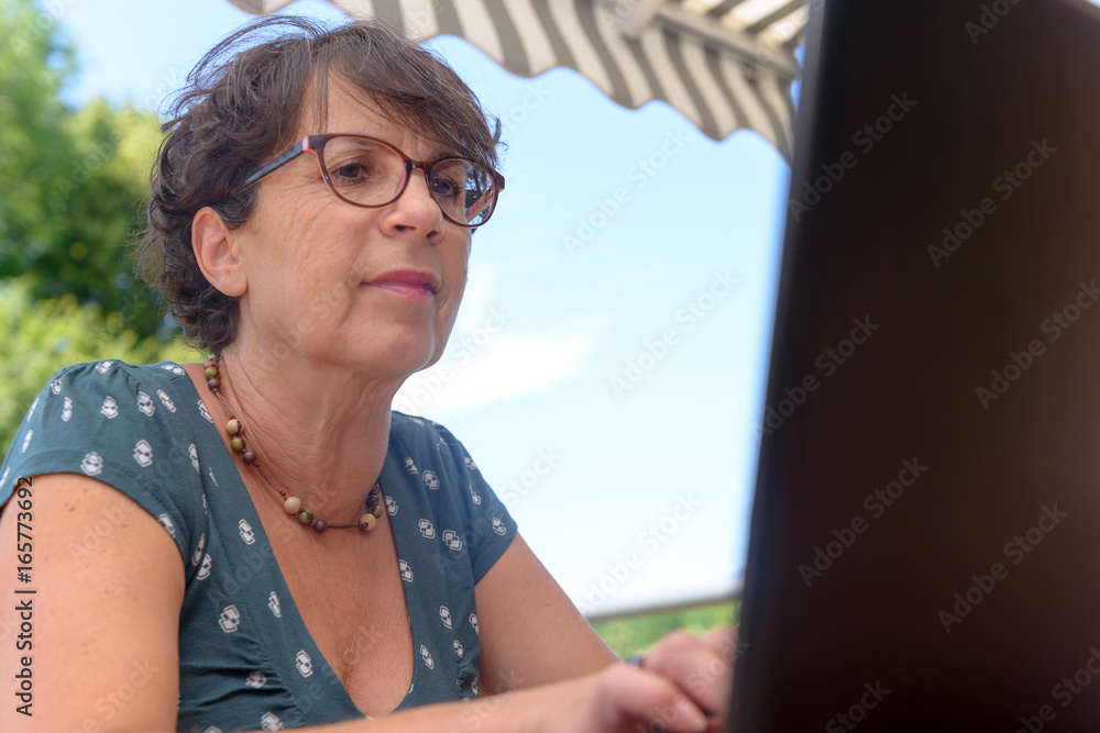 Modern casual woman sitting at garden with laptop