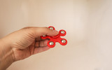 Bright red spinner in the form of a flower with 6 petals in the hand