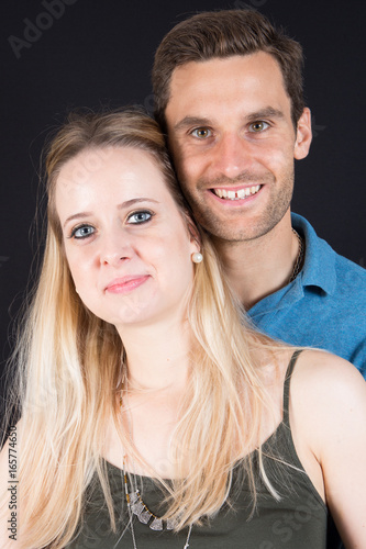Young couple standing on black background