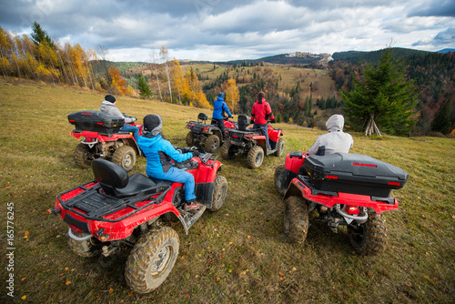 Fotografie Rear view group of five person riding quad bikes on hill and enjoying beautiful