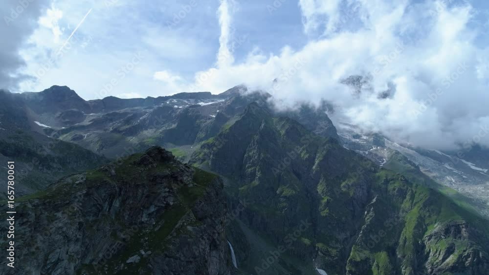 moving forward over majestic alpine mountain peak revealing valley in sunny cloudy summer.Europe Alps outdoor green nature scape mountains wild aerial establisher.4k drone flight establishing shot moving forward over majestic alpine mountain peak revealing valley in sunny cloudy summer.Europe Alps outdoor green nature scape mountains wild aerial establisher.4k drone flight establishing shot