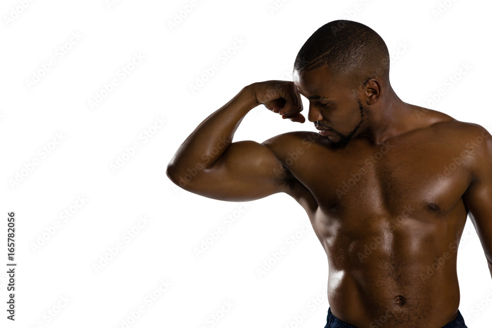 Shirtless male sportsman flexing muscles while standing against white background Shirtless male sportsman flexing muscles while standing against white background