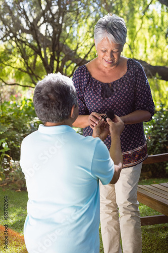 Senior man proposing woman by gifting ring in garden