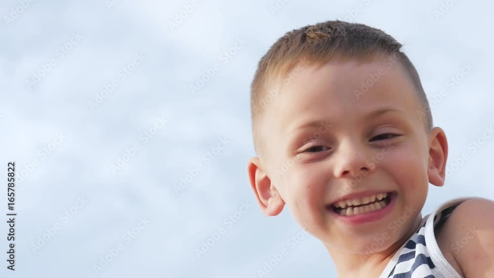 happy smiling little boy in sailor stripes shirt on sky background