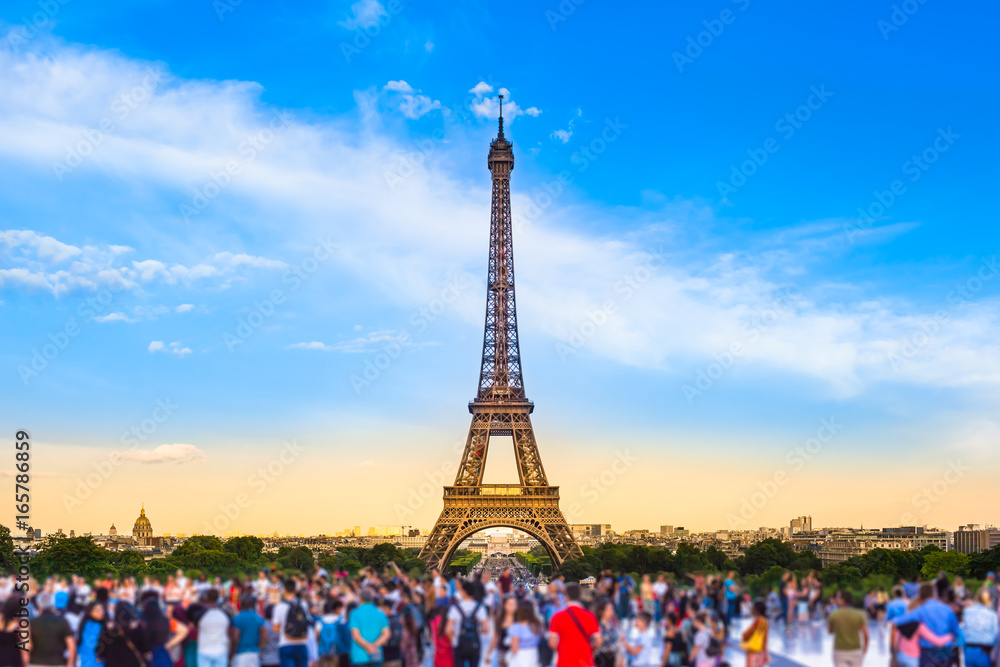 Fototapeta premium Paris Tourist Place / Colorful large group of unrecognizable people blurred in front of Paris Eiffel Tower at evening light (copy space)