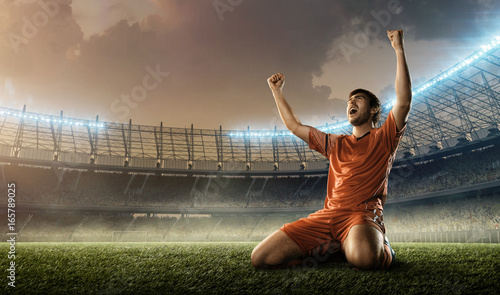 Fotografiet soccer player in red uniform celebrates a goal on a soccer stadium holding hands