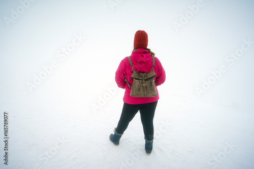 Back view of woman with backpack in snowstorm
