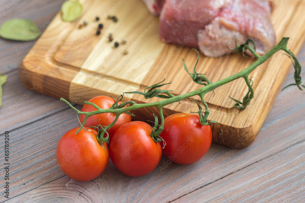 Fresh meat on the wooden table with spices and tomatoes Fresh meat on the wooden table with spices and tomatoes
