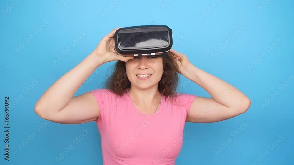 Happy young woman using a virtual reality headset on blue background Happy young woman using a virtual reality headset on blue background