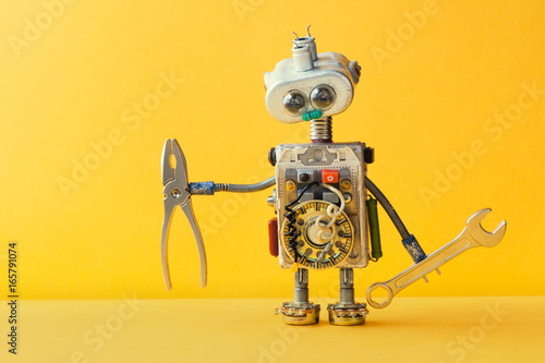Hand wrench pliers robot handyman on yellow background. Cyborg toy lamp bulb eyes head, electric wires, capacitors vintage resistors.
