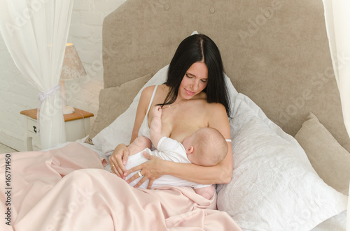 Breastfeeding. Young mother nursing baby. Family at home