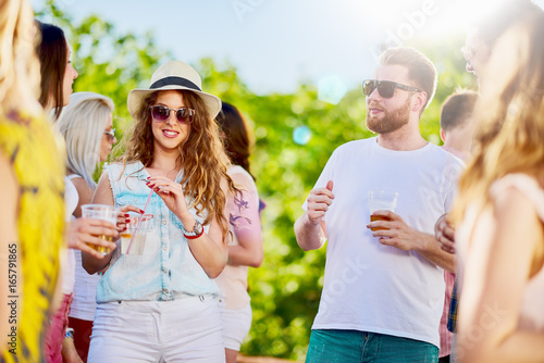 Group of people at outdoor party chatting, drinking and having good time