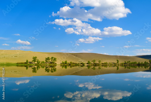 Quiet lake, yellow hills and blue sky in Altai mountains. White clouds reflected in water. Chuya prairie, Altay Republic, Siberia, Russia.