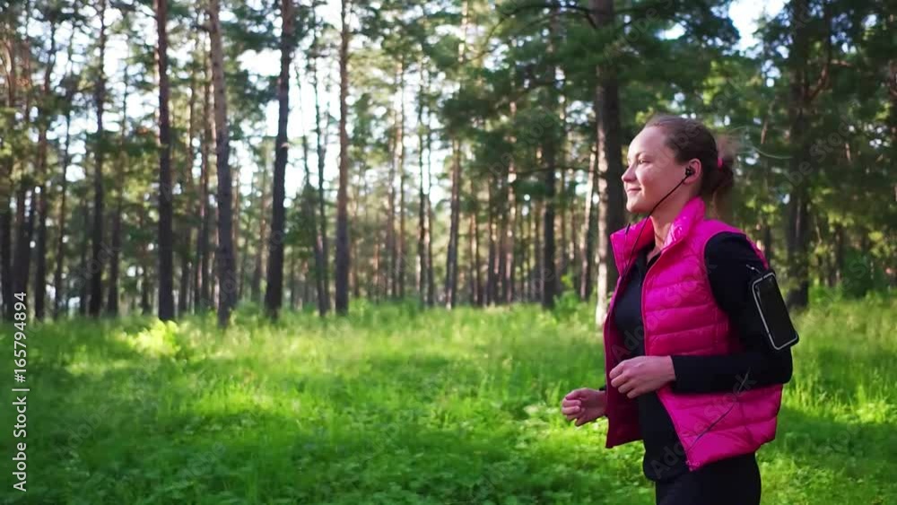 Pretty girl wearing sportswear and running in green forest at mountain during spring Pretty girl wearing sportswear and running in green forest at mountain during spring