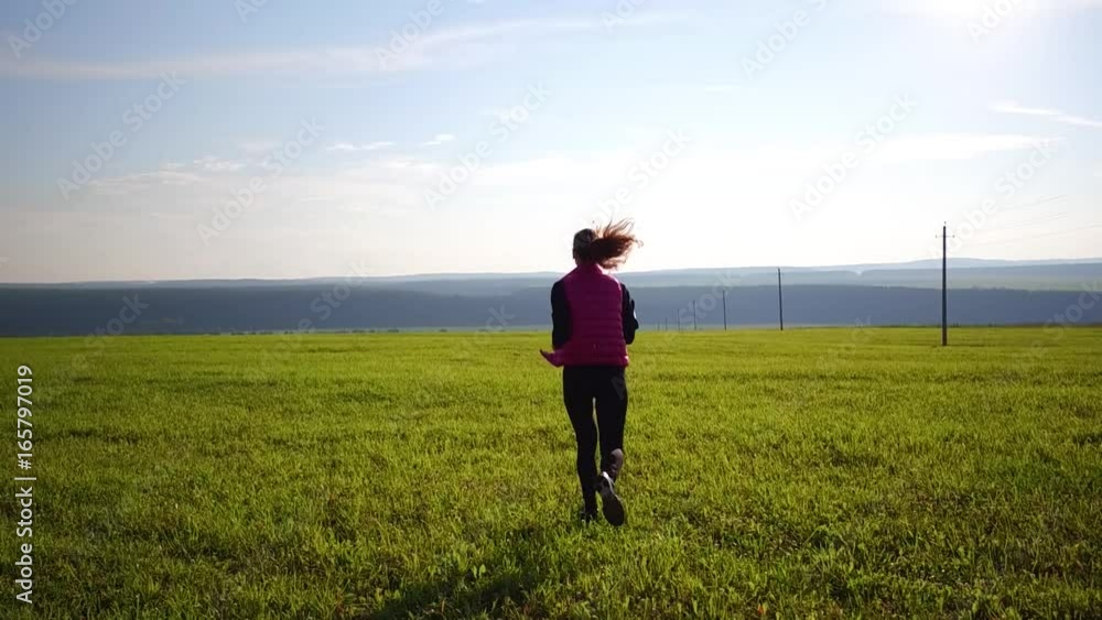 Pretty girl wearing sportswear and running in green field Pretty girl wearing sportswear and running in green field