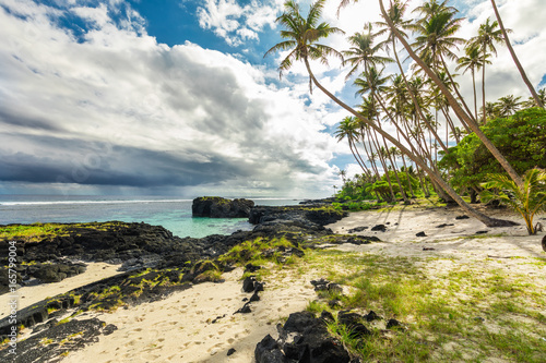 Tropical beach and ocean on Samoa Island with palm trees during afternoon photo