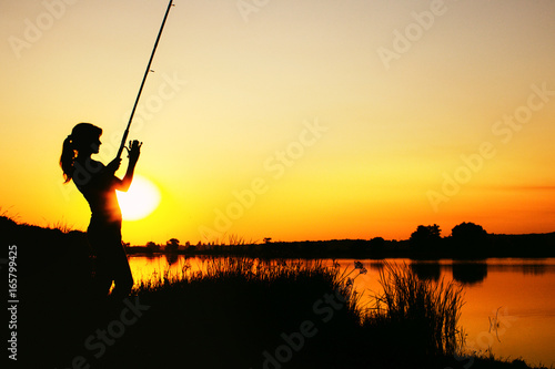Silhouette of a fishing woman at dawn