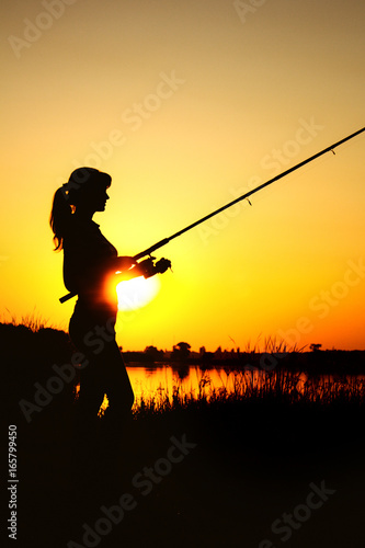 Silhouette of a woman with a fishing rod on nature