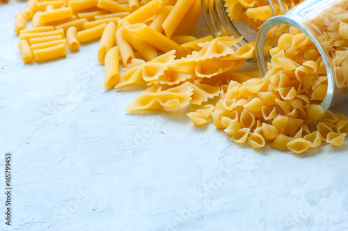 Assortment of raw pasta in a glass jar. White background.