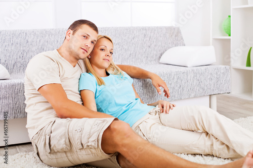 Happy couple sitting on the floor in the living room.
