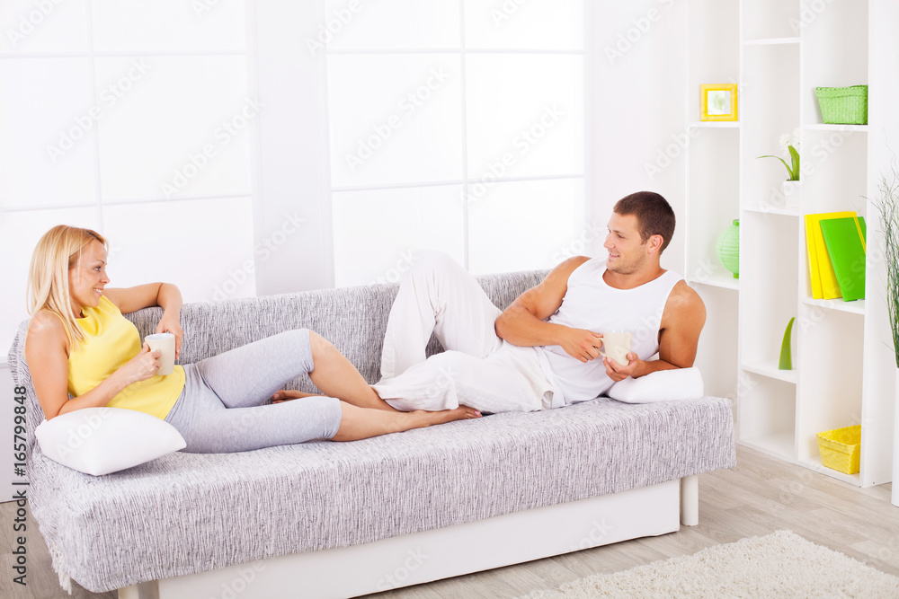 Happy couple drinking coffee on the sofa.