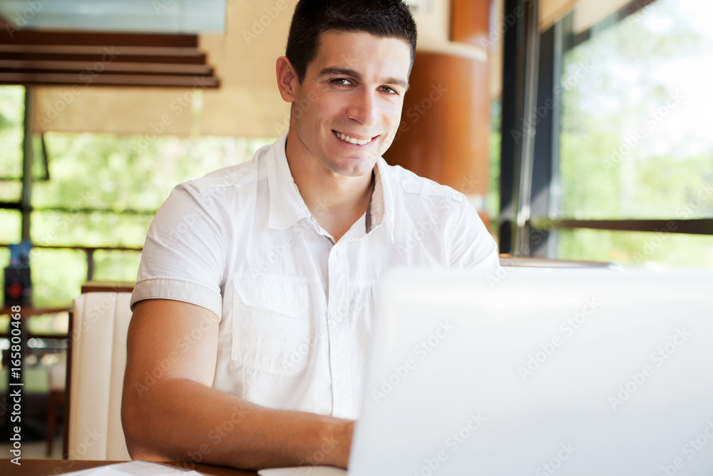 Young businessman working on laptop in cafeteria. Young businessman working on laptop in cafeteria.