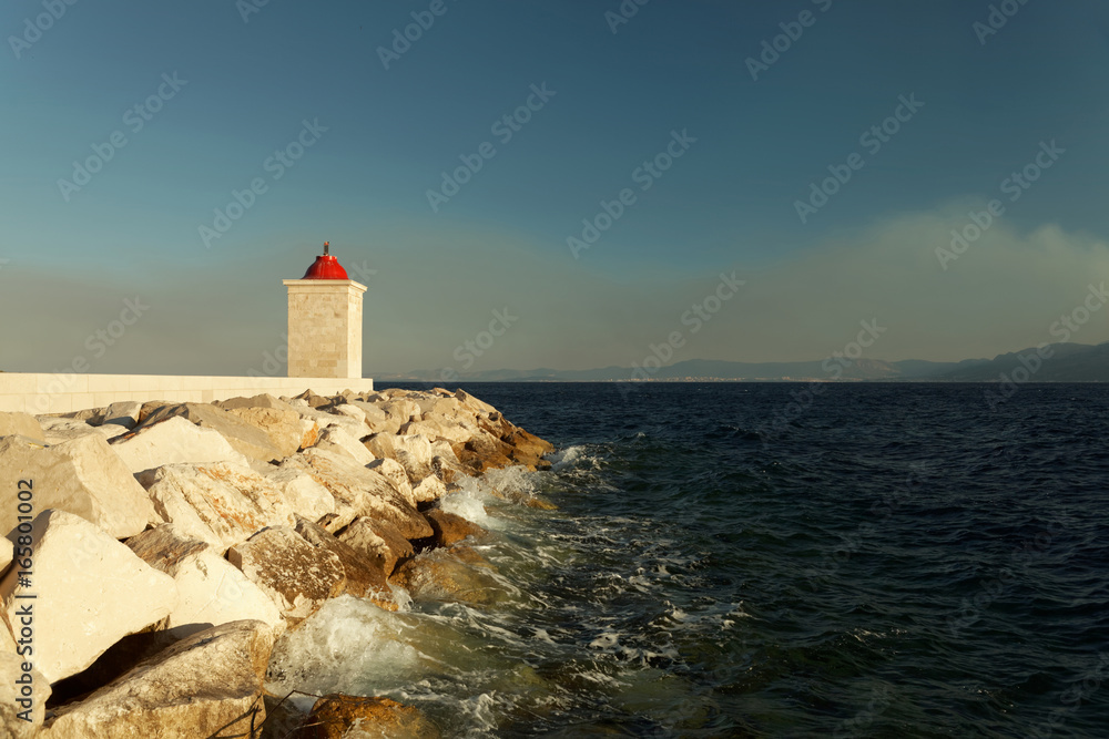 Lighthouse in the harbor of a of a small town on a stormy day - Croatia, island Brac