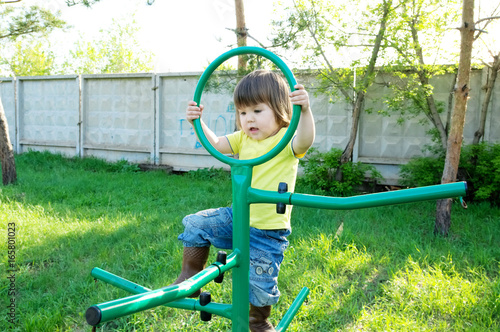 little girl playing outdoors. Kid on playground, children activity. Child having fun with curcle gym. Active healthy childhood concept photo