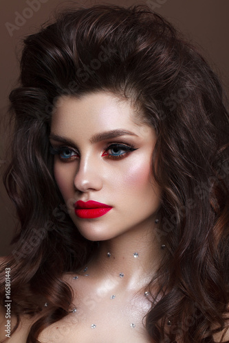 Beautiful young model with professional make up, perfect skin, volume hairdo. Red lips.