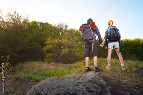 Man and woman traveler outdoors.Couple of Hikers holding their hands. Travel, vacation, holidays and adventure concept. Forest Mountain landscape background