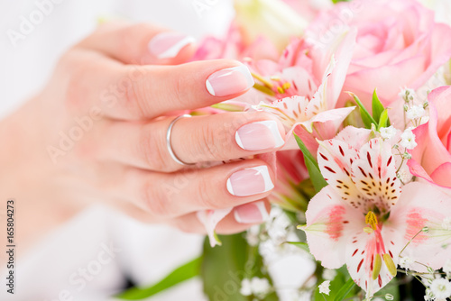 close-up view of female hand with beautiful manicure touching blooming flowers