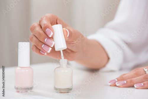 cropped shot of young woman applying nail polish while doing french manicure