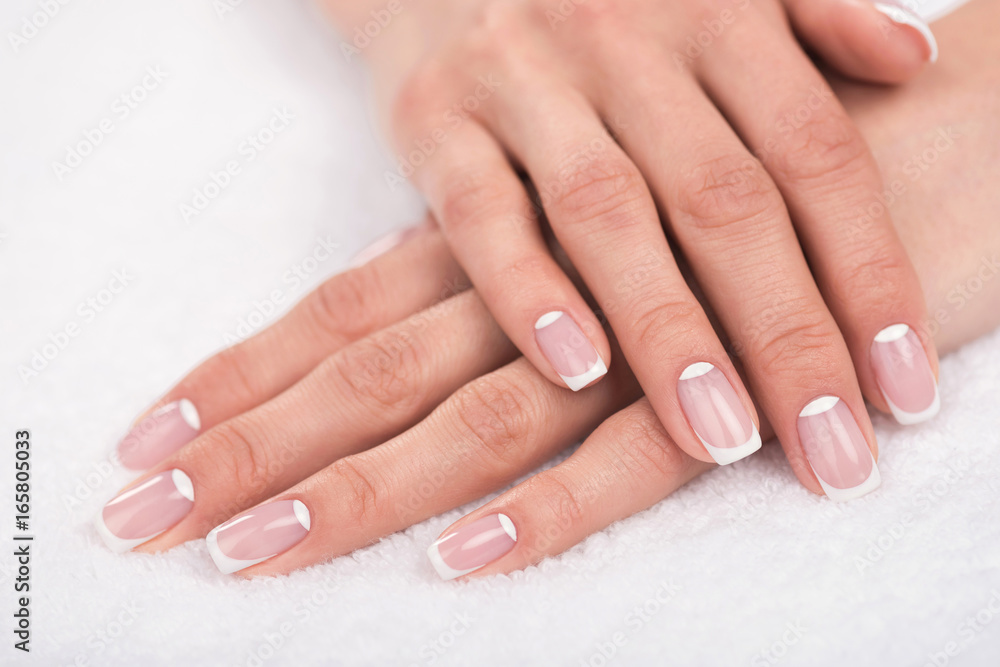 close-up view of beautiful female hands with french manicure on white