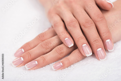 close-up view of beautiful female hands with french manicure on white